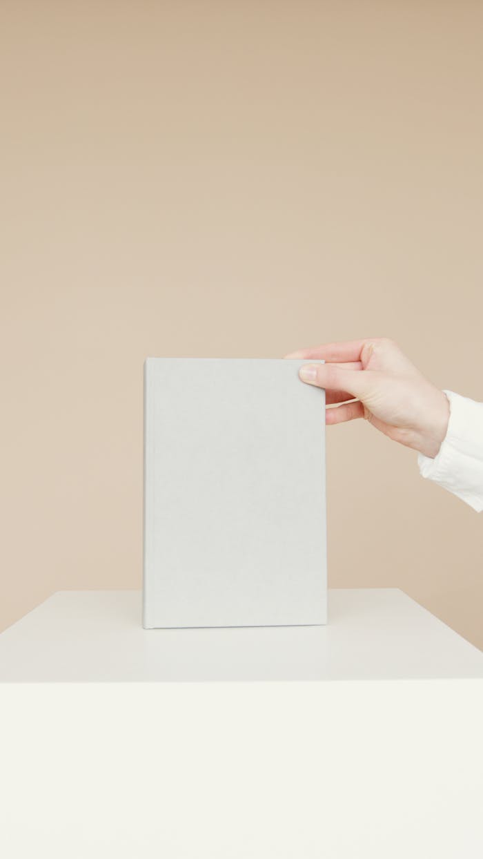 Simple minimalist image of a blank book being held by a person's hand, ideal for branding.